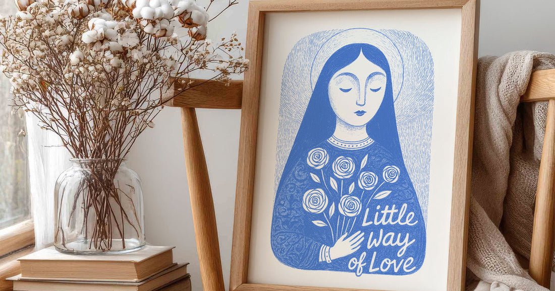 Blue St. Thérèse of Lisieux art print in a wooden frame beside cotton branches, books, and a linen blanket.