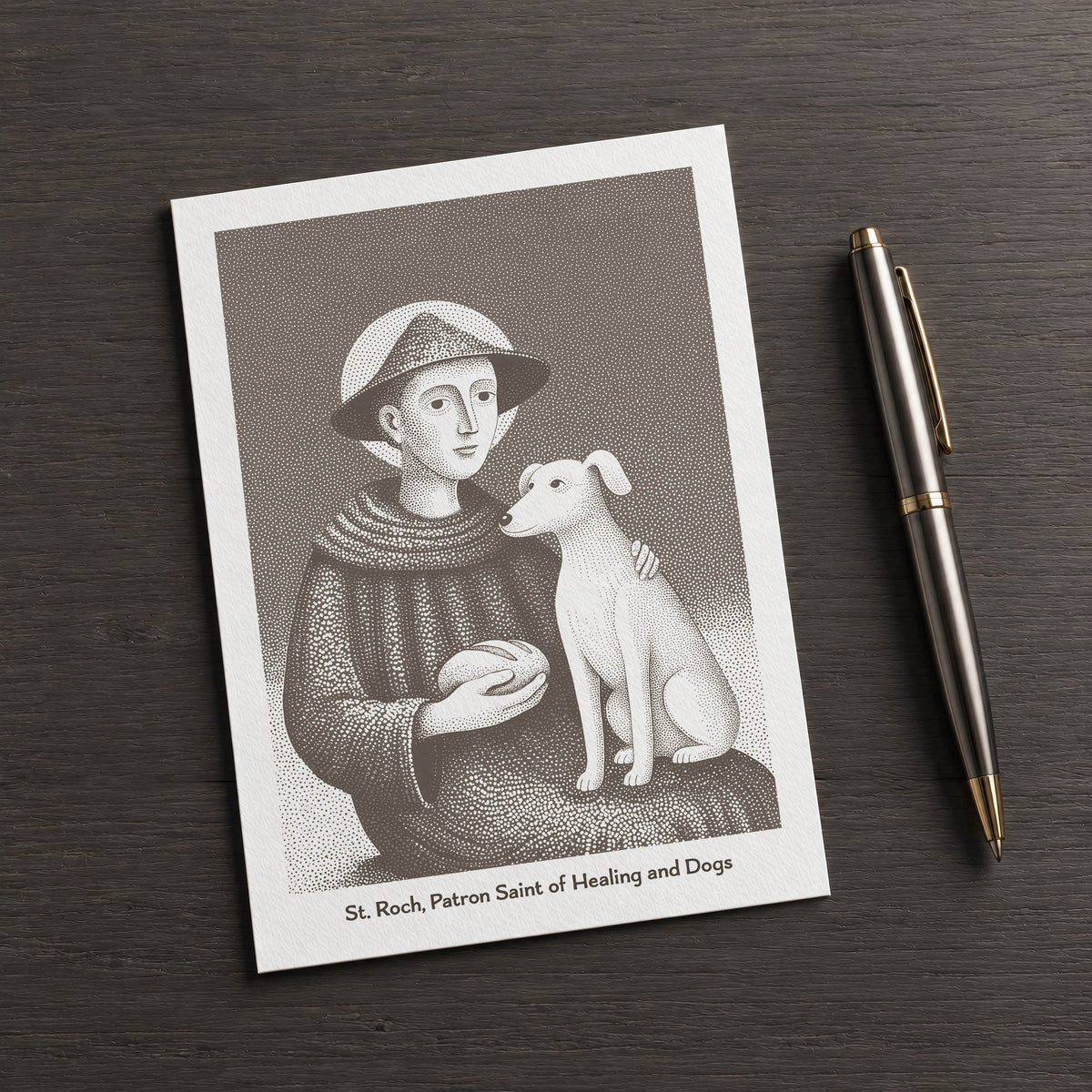 Brown St Roch card on a dark table beside a pen
