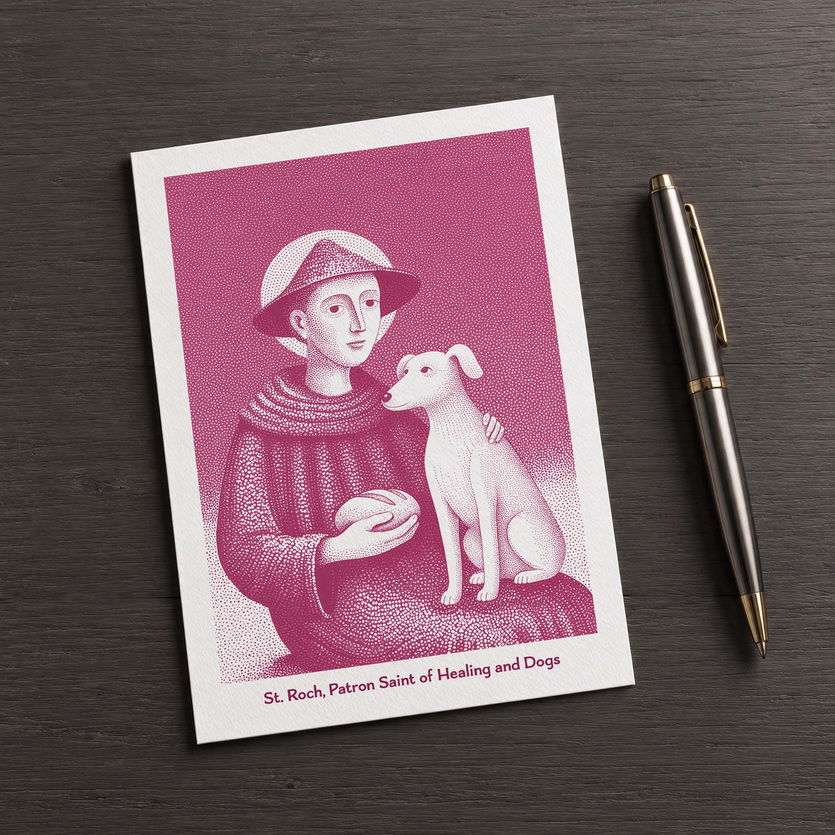 Pink St Roch card on a dark table beside a pen