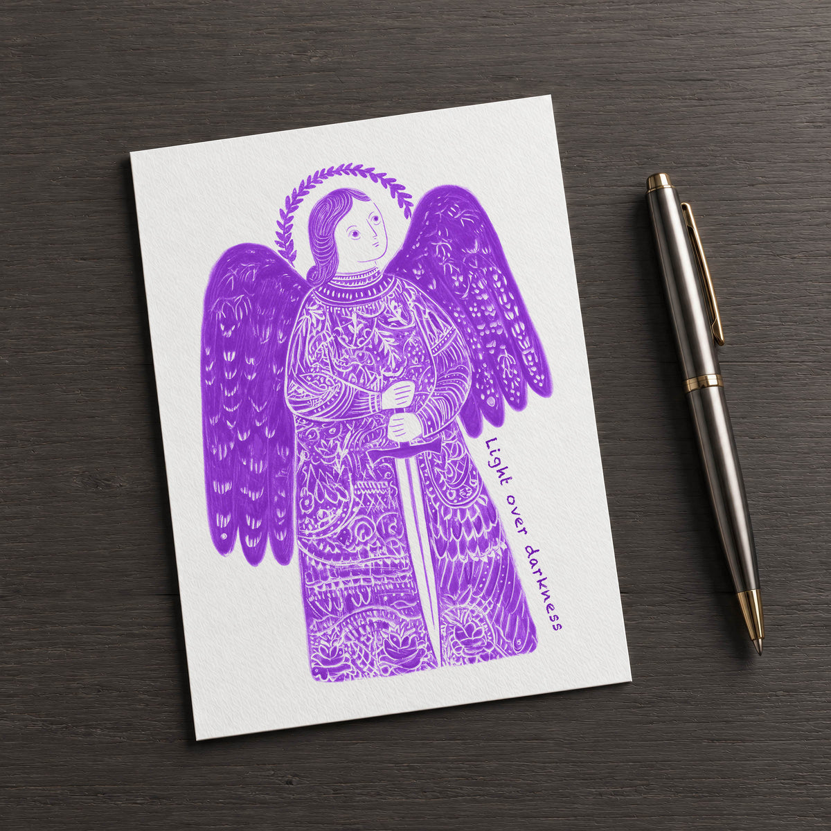 Purple St Michael the Archangel card on a dark table beside a pen