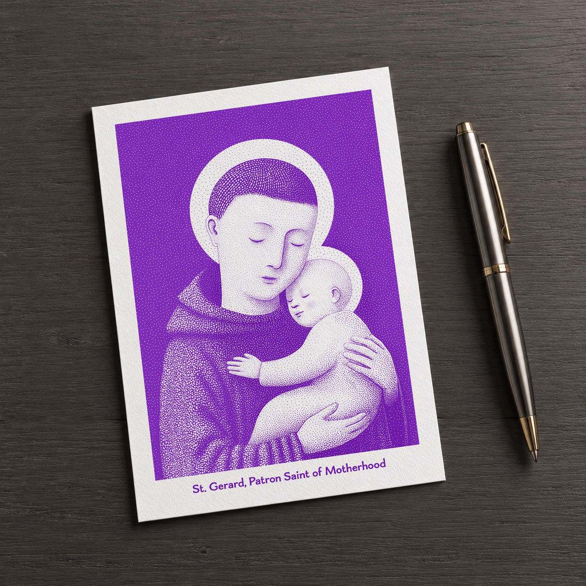 Purple St Gerard Majella card on a dark table beside a pen