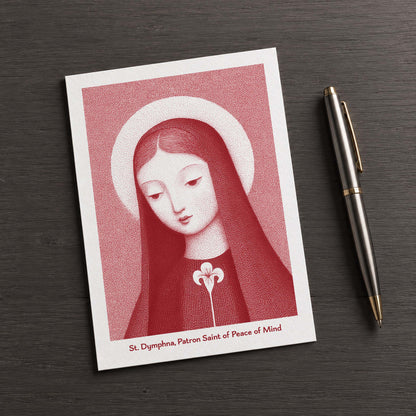 Red St Dymphna card on a dark table beside a pen